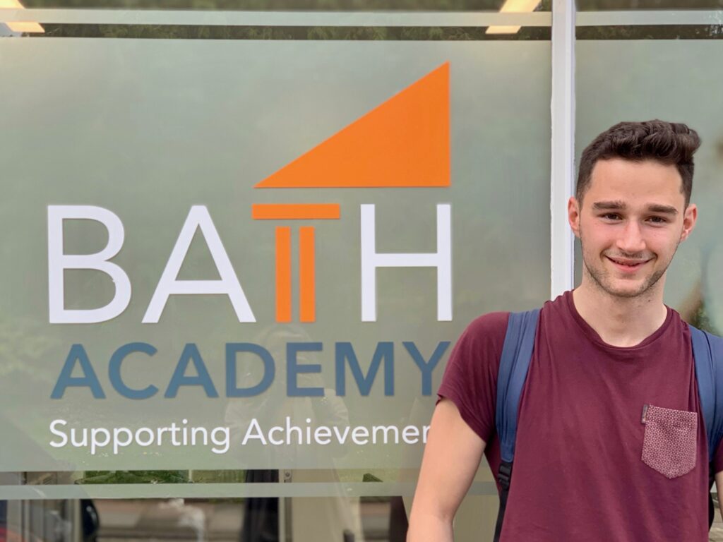 student in front of Bath Academy sign